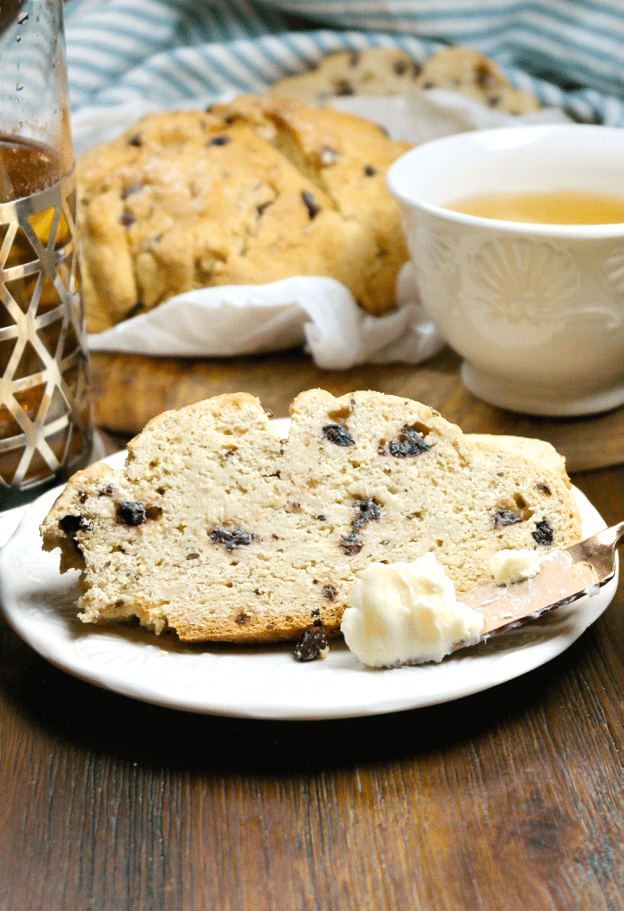 Slice Irish soda bread on a white plate with butter on a butter knife.