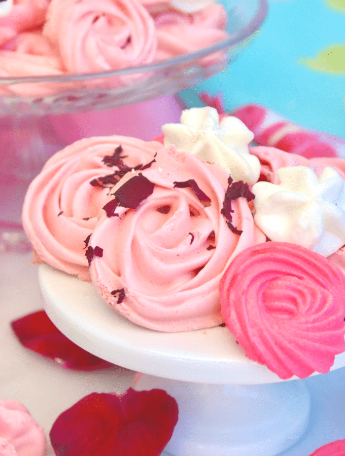A small white pedestal topped with pink and white meringue cookies.