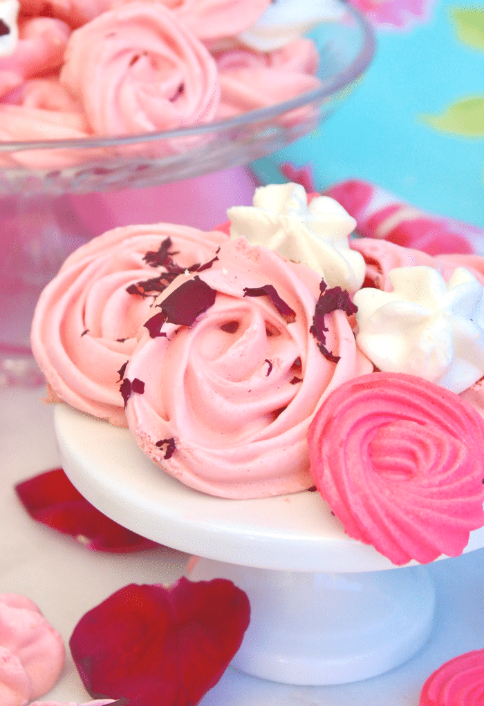 A small white pedestal topped with pink and white meringue cookies. 