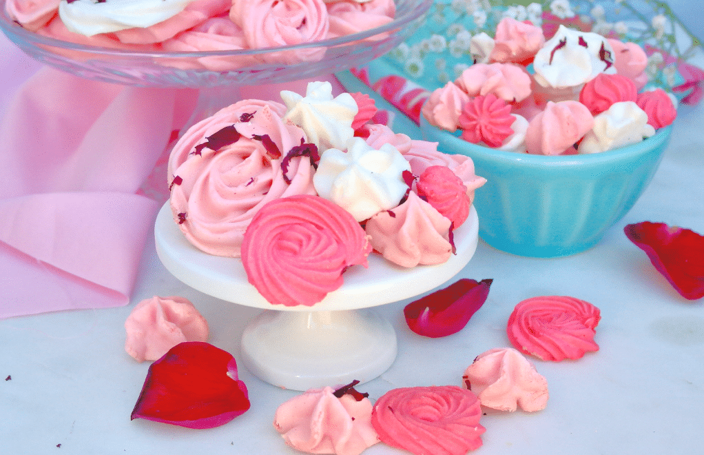 Mini cake plate and small teal bowl filled with rose meringue cookies. 