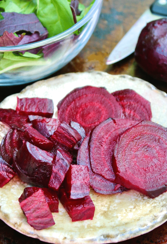 Roasted beets sliced and diced on a salad plate ready to add to a bowl of green salad. 