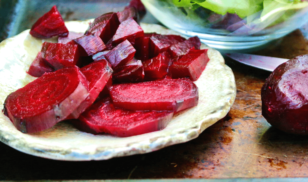 Roasted beets on on a tan plate sliced ready to eat. 