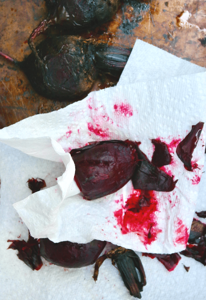 Removing skin of cooked beets with a paper towel. 
