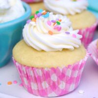 Vanilla cupcake topped with vanilla frosting on a white platter.