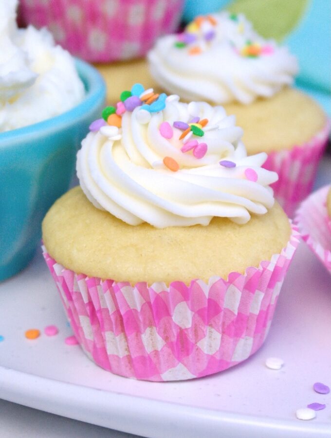 Vanilla cupcake topped with vanilla frosting on a white platter.