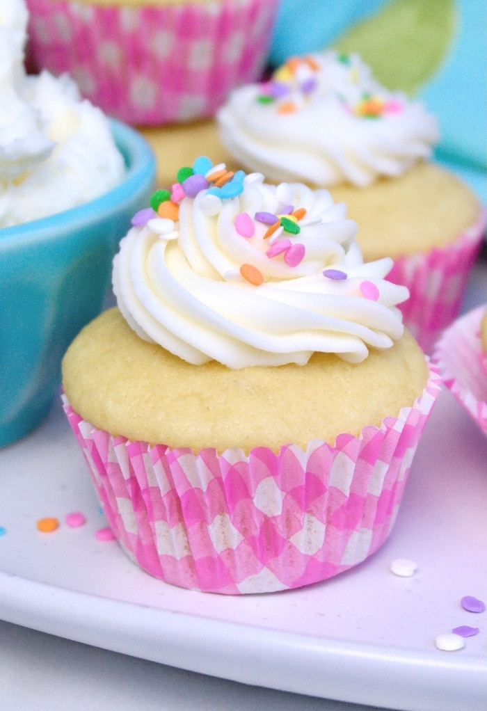 Vanilla cupcake topped with vanilla frosting on a white platter. 