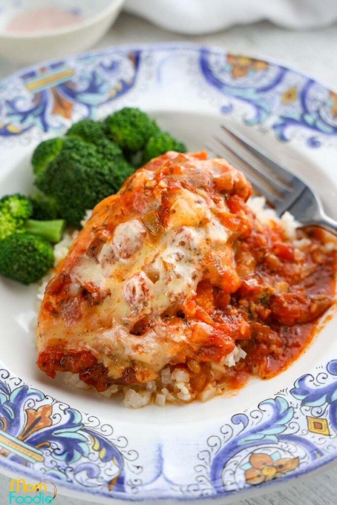 top view of cooked chicken breasts topped with salsa and cheese and a side of broccoli