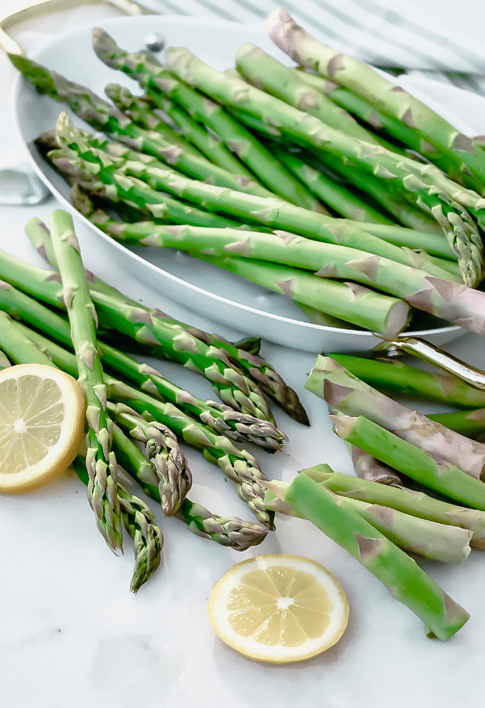 Fresh asparagus cleaned and sliced placed in a white serving platter.