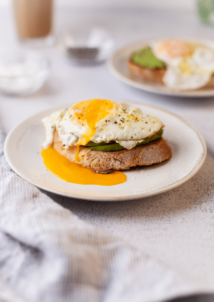 Sunny side up egg with the yolk oozing over avocado toast. 