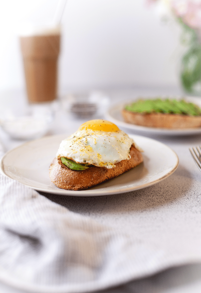 Avocado toast and egg on a white plate ready to eat