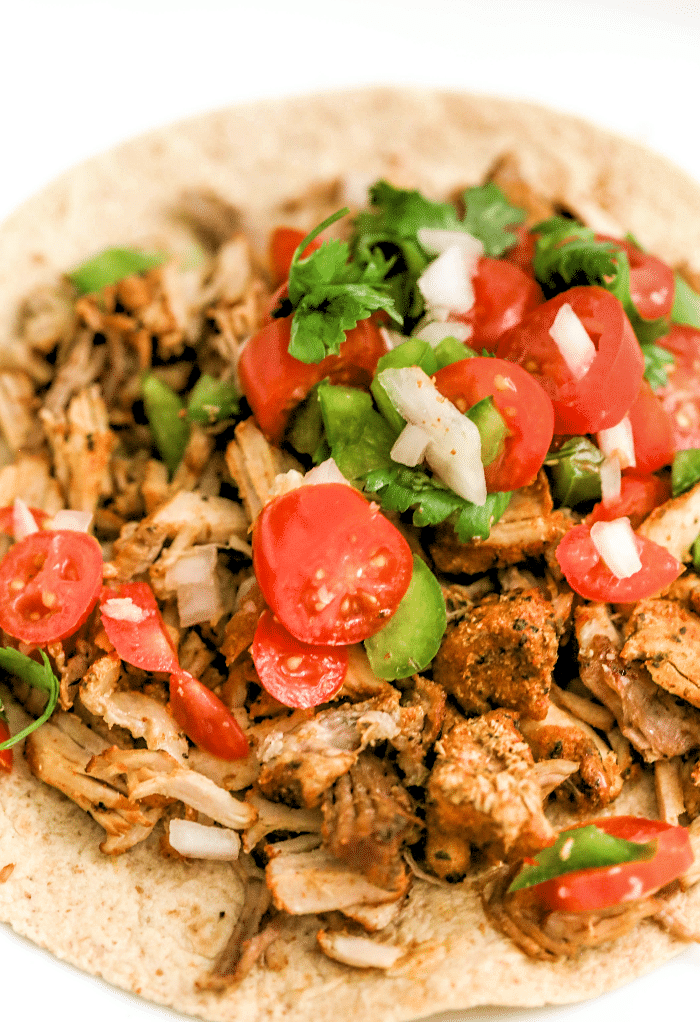 Top view of pork carnitas on a tortilla.