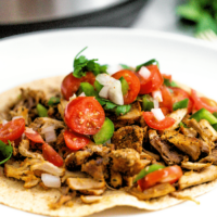 A close view of pork carnitas made in an instant pot on a white plate ready to eat.