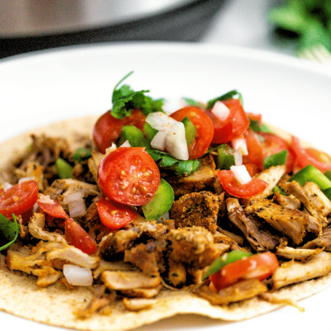 A close view of pork carnitas made in an instant pot on a white plate ready to eat.