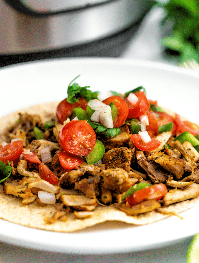 A close view of pork carnitas made in an instant pot on a white plate ready to eat.