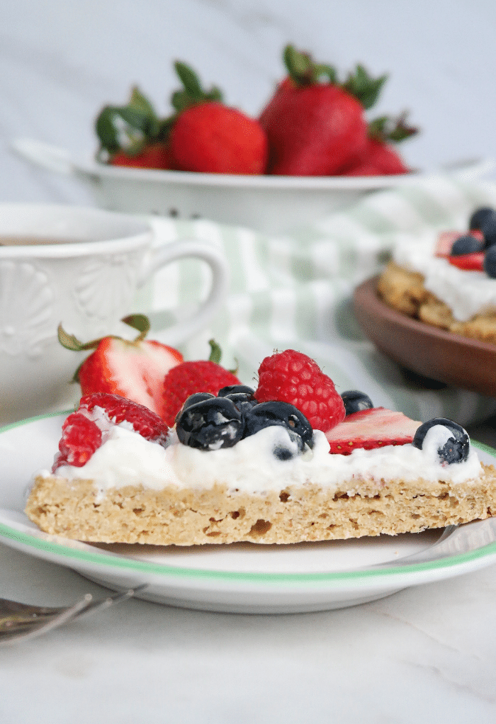  A slice of fruit pizza on a white plate with a light green rim. 