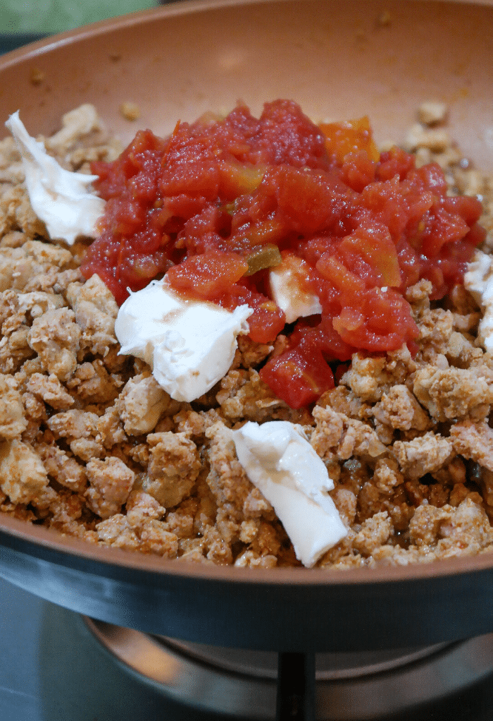 Cooked ground turkey in a skilled with cream cheese and diced tomatoes. 