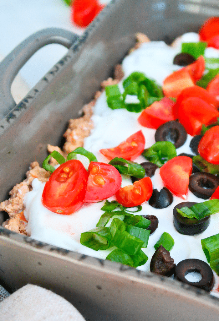 Ingredients layered on a casserole dish to make keto taco casserole. 