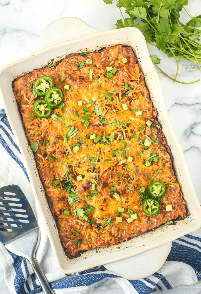 Cooked vegetarian enchiladas in a white casserole dish. 