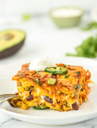 A slice of vegetarian enchilada casserole on a white plate ready to eat.