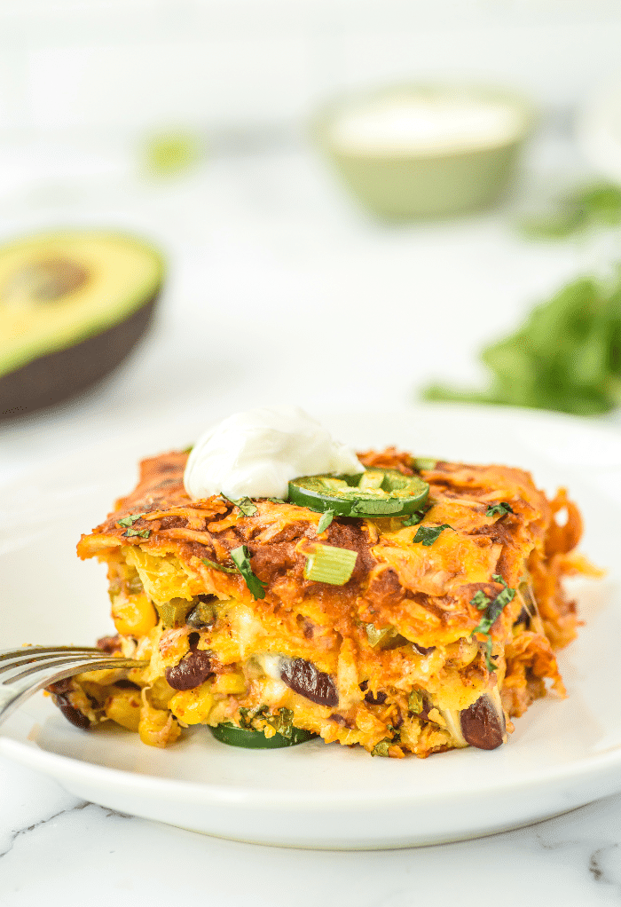 A slice of vegetarian enchilada casserole on a white plate ready to eat.  