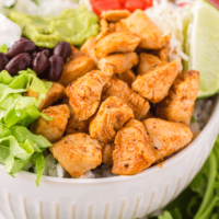 Chipotle chicken bowl with lettuce beans topped with lime.