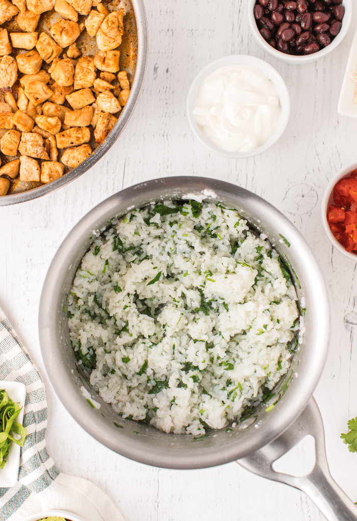 Cilantro mixed in white rice in a saucepan. 