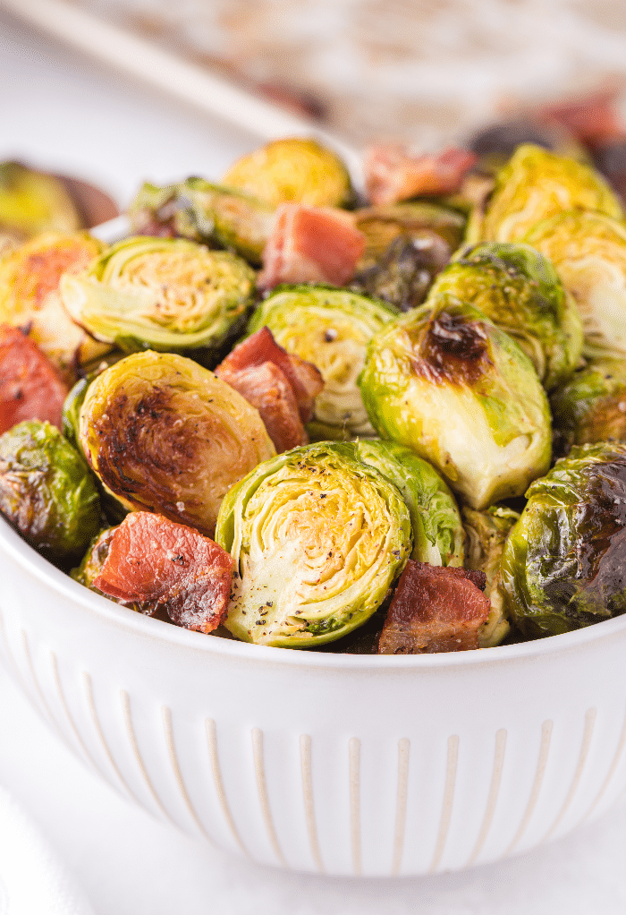 A white bowl filled with roasted Brussel sprouts with bacon.