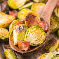 A wooden spoon full of roasted Brussels sprouts.