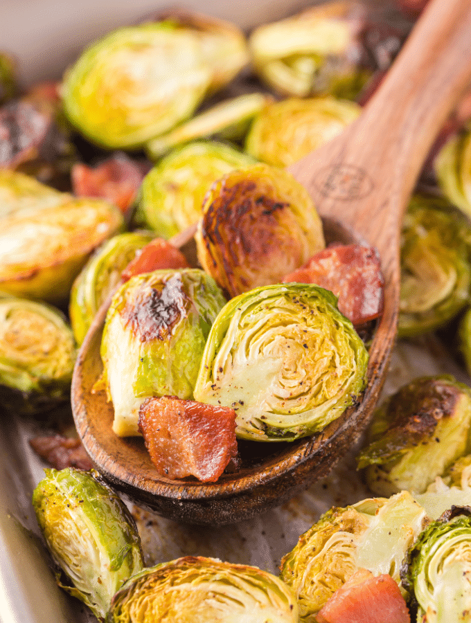 A wooden spoon full of roasted Brussels sprouts.