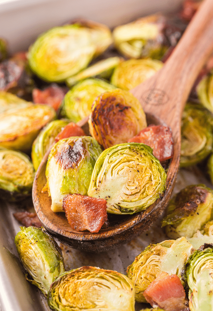 A wooden spoon full of roasted Brussels sprouts.