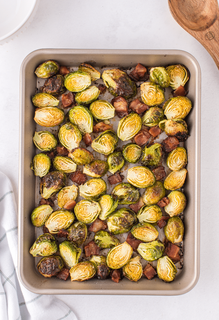 Cooked Brussels sprouts with bacon on a baking sheet.