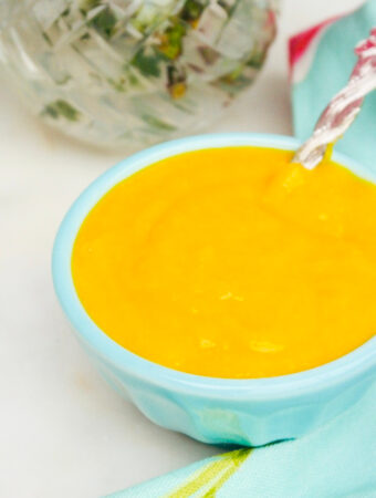 A teal bowl with mango pureed into a sauce.