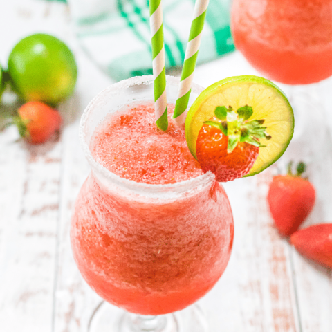 Virgin strawberry daiquiri in clear glasses topped with slice of lime and fresh strawberry.