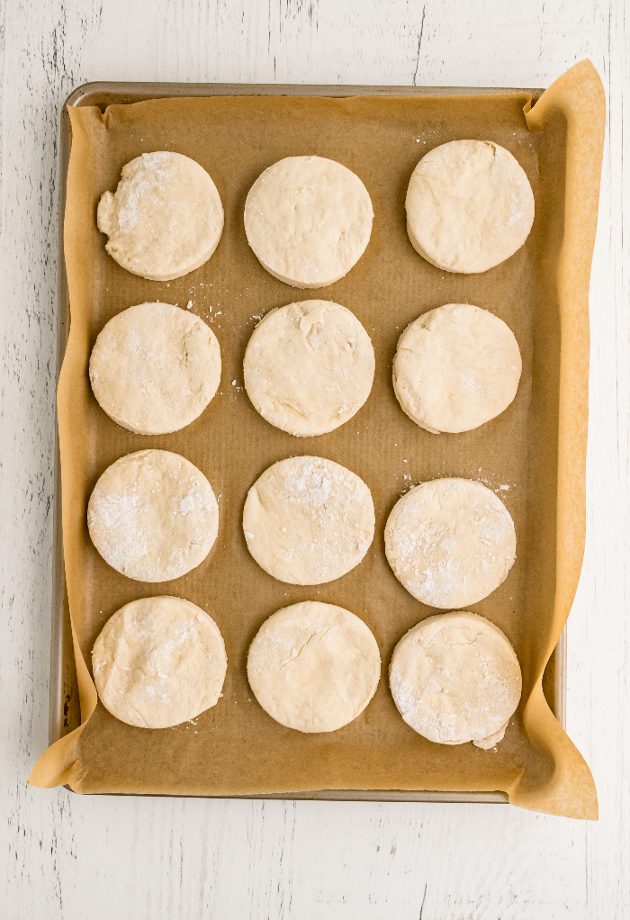 Unbaked biscuits on a baking sheet covered with brown parchment paper ready to bake. 