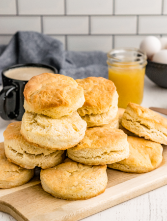 A dozen homemade buttermilk biscuits on a brown cutting board ready to enjoy.