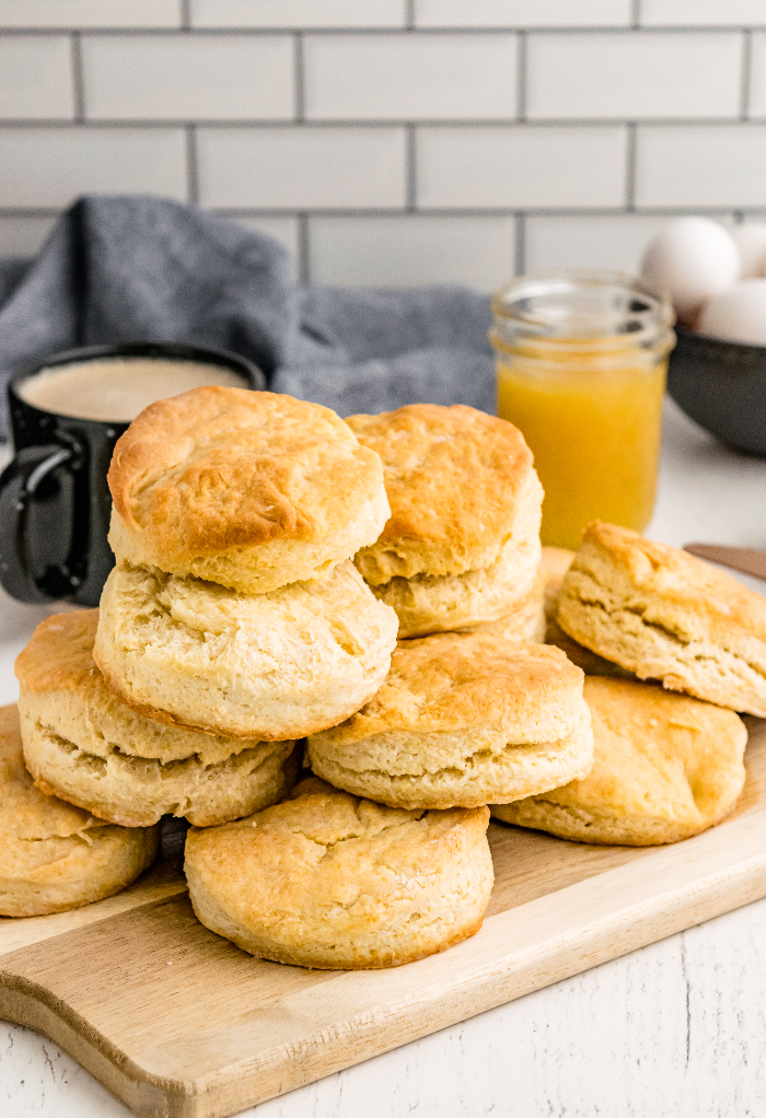 A dozen homemade buttermilk biscuits on a brown cutting board ready to enjoy.