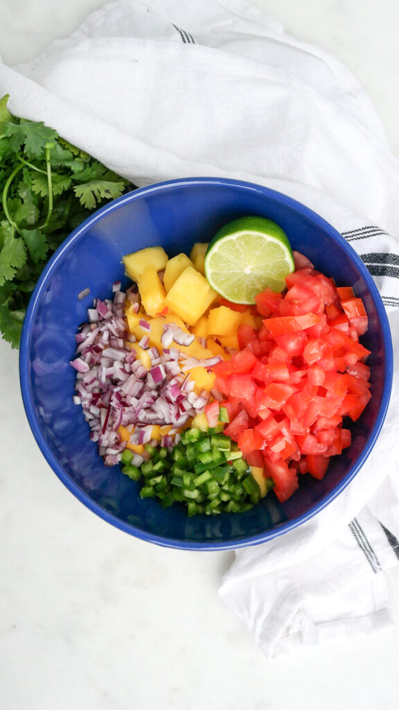 Ingredients to make a fruit pico de gallo in a blue serving bowl.