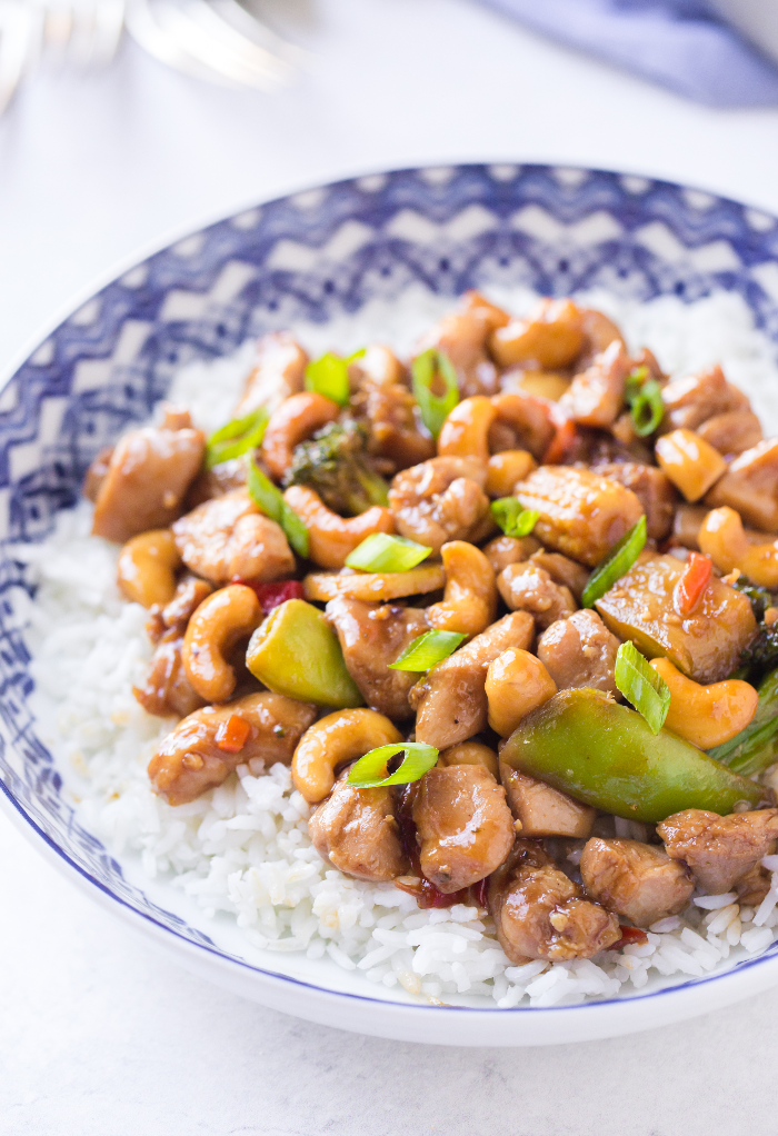 A white bowl with a blue rim filled with rice topped with Teriyaki Stir Fry Chicken. 