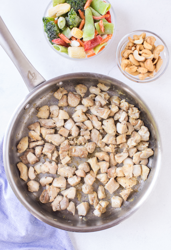 Diced chicken in a skillet cooking.