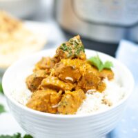Butter chicken in a white bowl with rice.