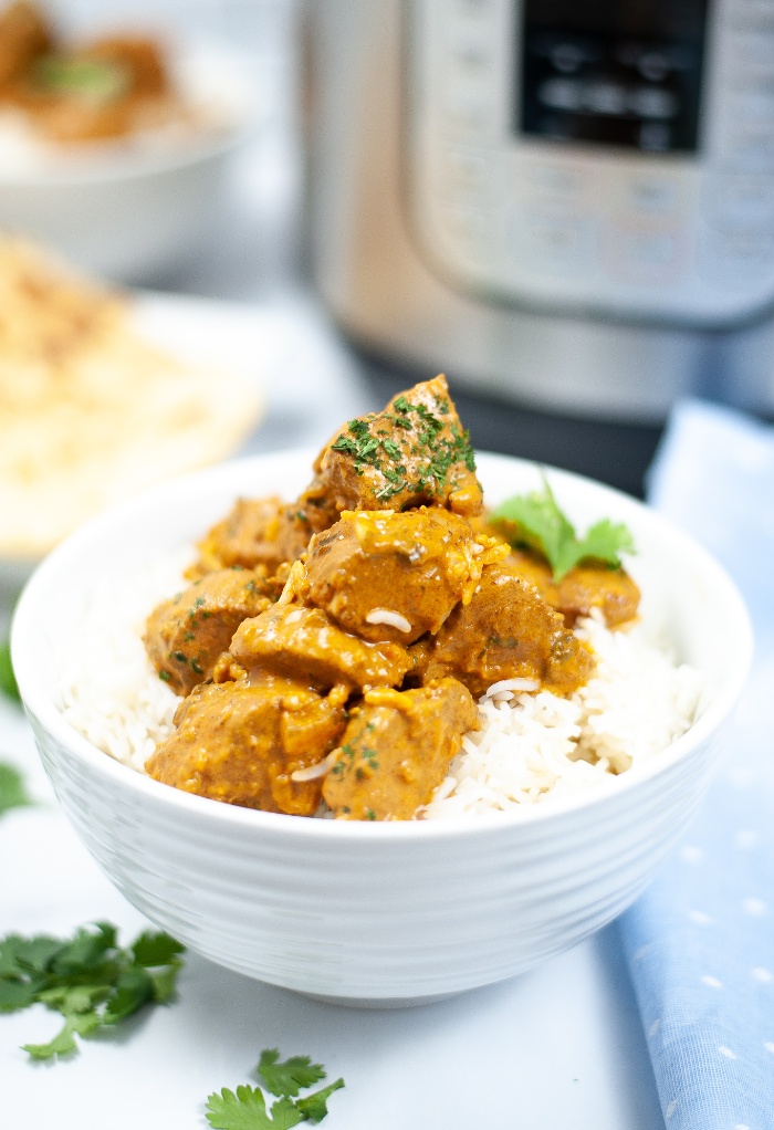 Butter chicken in a white bowl with rice.