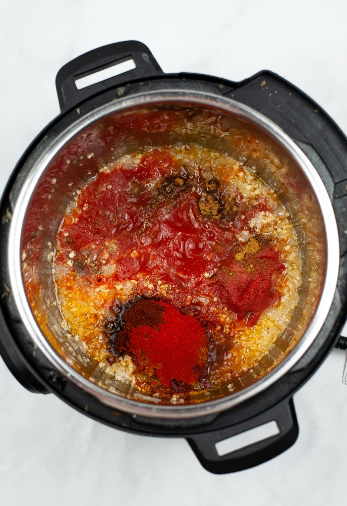 Spices added to sautéed onion in an Instant Pot. 