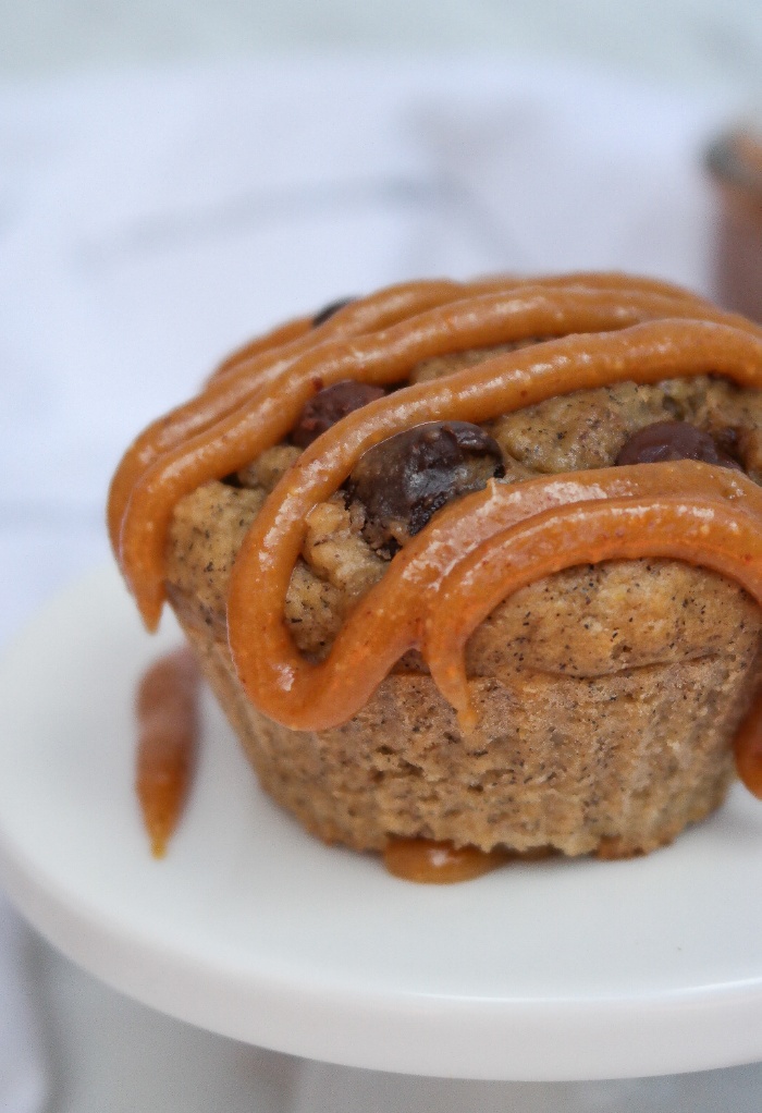 A muffin with a drizzle of peanut butter over the top.