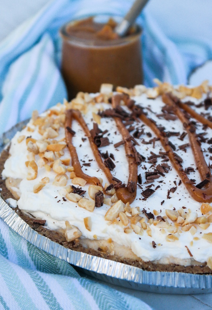 Peanut butter pie topped with a peanut drizzle and whipped cream.