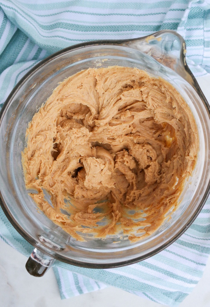 Peanut butter mixed with cream cheese in a clear bowl.