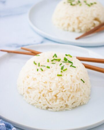 A plate with sticky rice with chopsticks on the side.