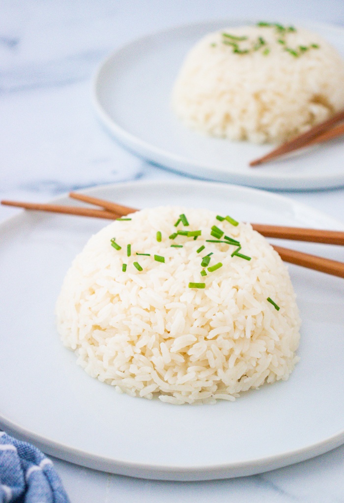 A plate with sticky rice with chopsticks on the side.