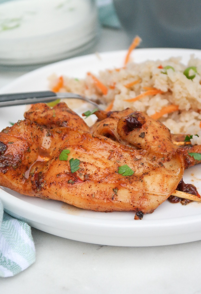 A white plate with chicken and cauliflower rice. 