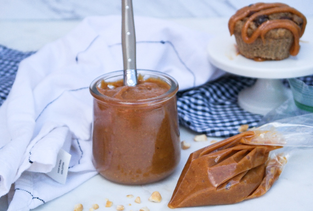 Peanut butter sauce with a pastry bag and muffin in the back.