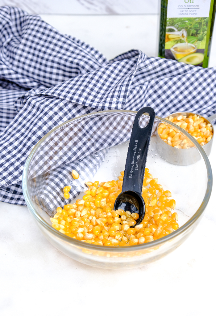 Popcorn kernels in a glass mixing bowl with oil for popping.